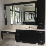 A bathroom with a huge mirror and black cabinets
