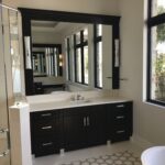 A bathroom mirror with black cabinets