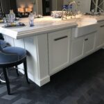 A white counter that serves as a dining area and sink