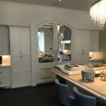 A dining room with white cabinets and mirrors